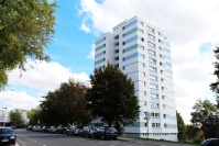 Punkthochhaus mit 12 Etagen, Fassade weiß und blau, an einer Straße.