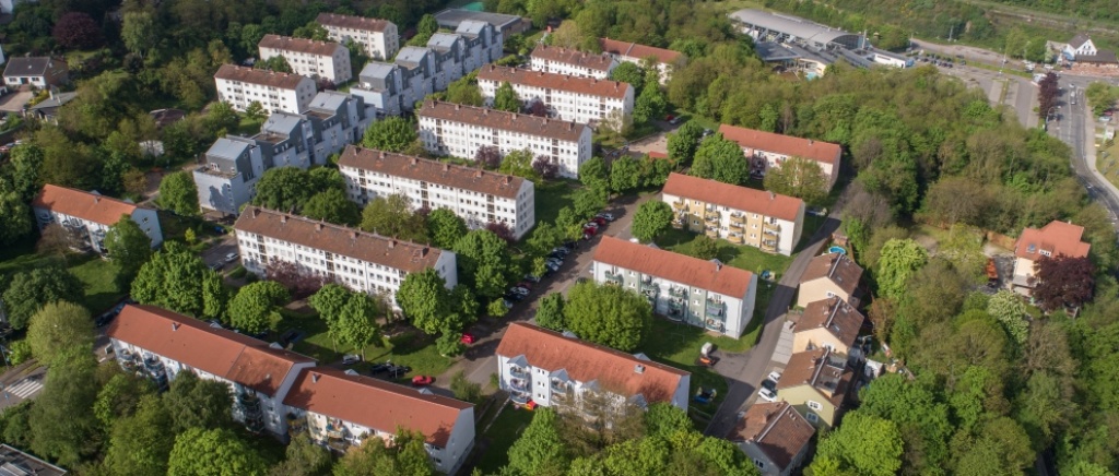 Mehrfamilienhäuser mit drei oder vier Etagen mit Grünflächen und Bäumen