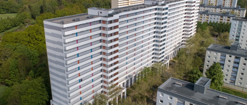 Luftbild saniertes Hochhaus 15 Etagen mit drei neuen Aufzugstürmen. Fassade weiß und grau, Streifen.