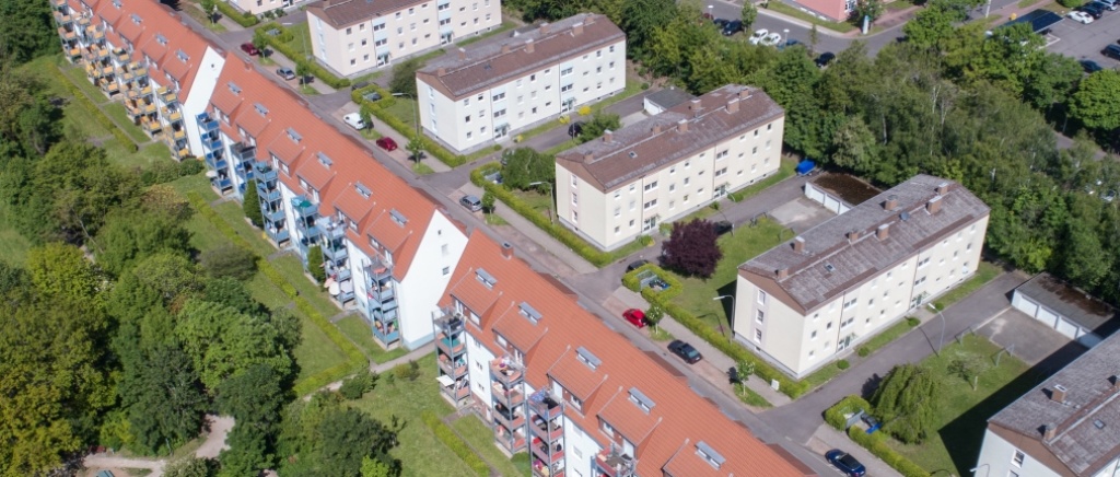 Altbauten mit sanierten Fassaden in weiß und angebauten Balkonen in gelb, blau und rot. 