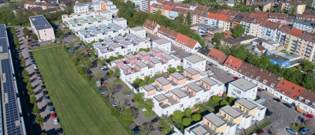 6 Wohnhöfe mit dreigeschossigen Häusern mit Flachdach. Helle Fassaden mit Farbakzenten. Die Höfe sind begrünt. 