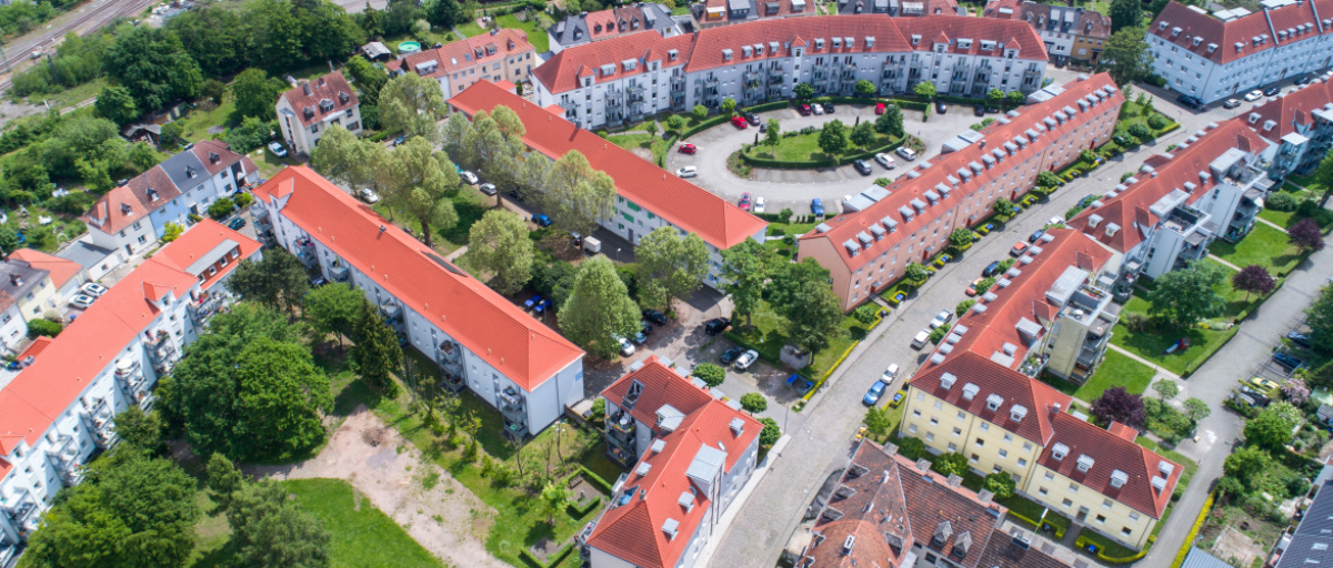 Sanierte Altbauten mit hellen Fassaden und neuen Dächern, dazwischen gestaltete Innenhofe mit Bewuchs.