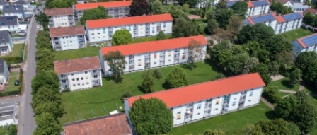 sanierte Wohnhäuser mit 3 Etagen, Satteldächern, helle Fassaden. Rundum Grünflächen mit Bäumen