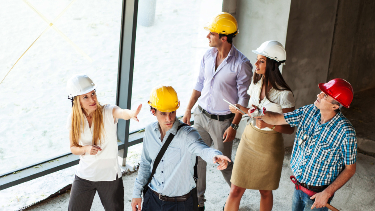 Mehrere Menschen mit Helmen in einem Rohbau