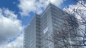 Obere Stockwerke eines Hochhauses, 12 Wohnetagen, mit Baugerüst und Netzen