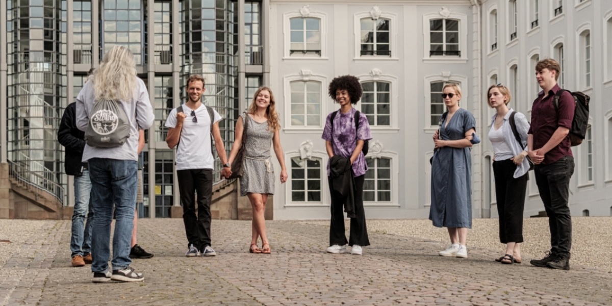 Gruppe von Touristen während einer Stadtführung vor dem Saarbrücker Schloss