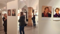 Blick in den Hauberrisser Saal mit Besucherinnen vor weißen Stellwänden, auf denen Portraits zu sehen sind