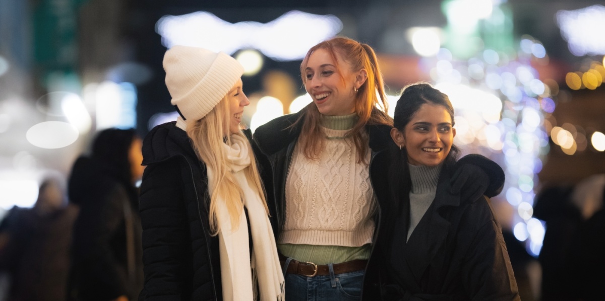 Drei Freundinnen schlendern mit Einkaufstüten durch die winterliche Innenstadt