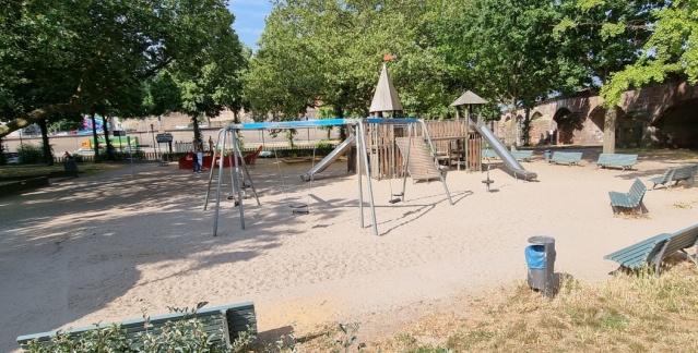 Aire de jeux près du théâtre national avec des arbres, un château à grimper et des balançoires