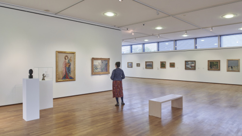 Besucherin im Innenraum der Modernen Galerie, Kunstwerke an den Wänden, Präsentation der Exponate in Säulen und Ruhebank