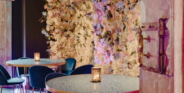 Das Innere des Lokals mit Tischen und Blumenwand im Hintergrund Das Innere des Lokals mit Tischen und Blumenwand im Hintergrund