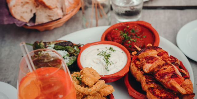 Ansicht von oben: Zwei Teller mit verschiedenen Tapas und Aufstrichen, sowie Brot, ein Glas Aperol Spritz und ein Glas Wasser Ansicht von oben: Zwei Teller mit verschiedenen Tapas und Aufstrichen, sowie Brot, ein Glas Aperol Spritz und ein Glas Wasser