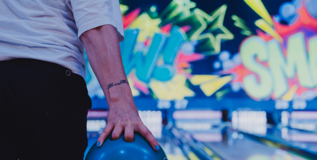 Man with bowling ball in hand at the start of the bowling alley, ready to throw