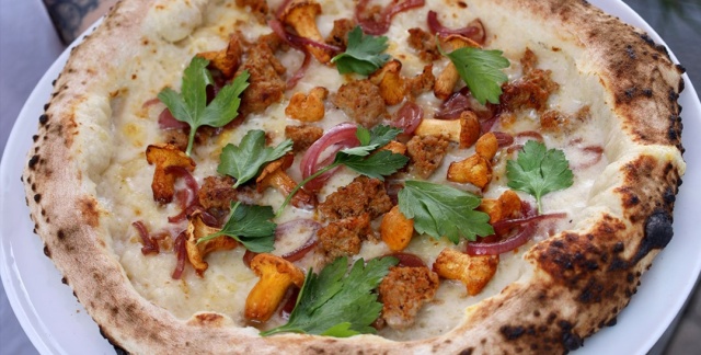Pizza "Beppe" mit Parmesan-Crème, Parmigiano DOP, Provolone, Kräuterseitlinge, Bliesgau Iberico Salsiccia, karamellisierte Zwiebeln und Blattpetersilie Pizza "Beppe" mit Parmesan-Crème, Parmigiano DOP, Provolone, Kräuterseitlinge, Bliesgau Iberico Salsiccia, karamellisierte Zwiebeln und Blattpetersilie