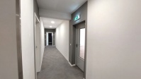 Etagenflur mit grauem Boden und Zugang zu Apartments, Wände, Decken und Türen weiß