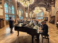 Eine Frau singt, von einem Klavier begleitet, in einem Festsaal