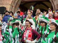 Mehrere kostümierte Männer und Frauen stehen lachend vor dem Rathausportal und halten gemeinsam einen großen Schlüssel.