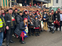 Eine große Gruppe kostümierter Teilnehmerinnen und Teilnehmer steht vor einem Motivwagen im Piratenstil und posiert für ein Gruppenfoto.