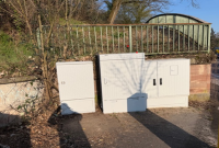 Drei weiße Versorgungskästen vor einer niedrigen Mauer mit Metallgeländer