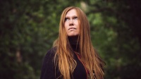 Rothaarige Frau vor begrünten Hintergrund 