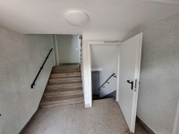 helles Treppenhaus mit offener Kellertür, Steinboden